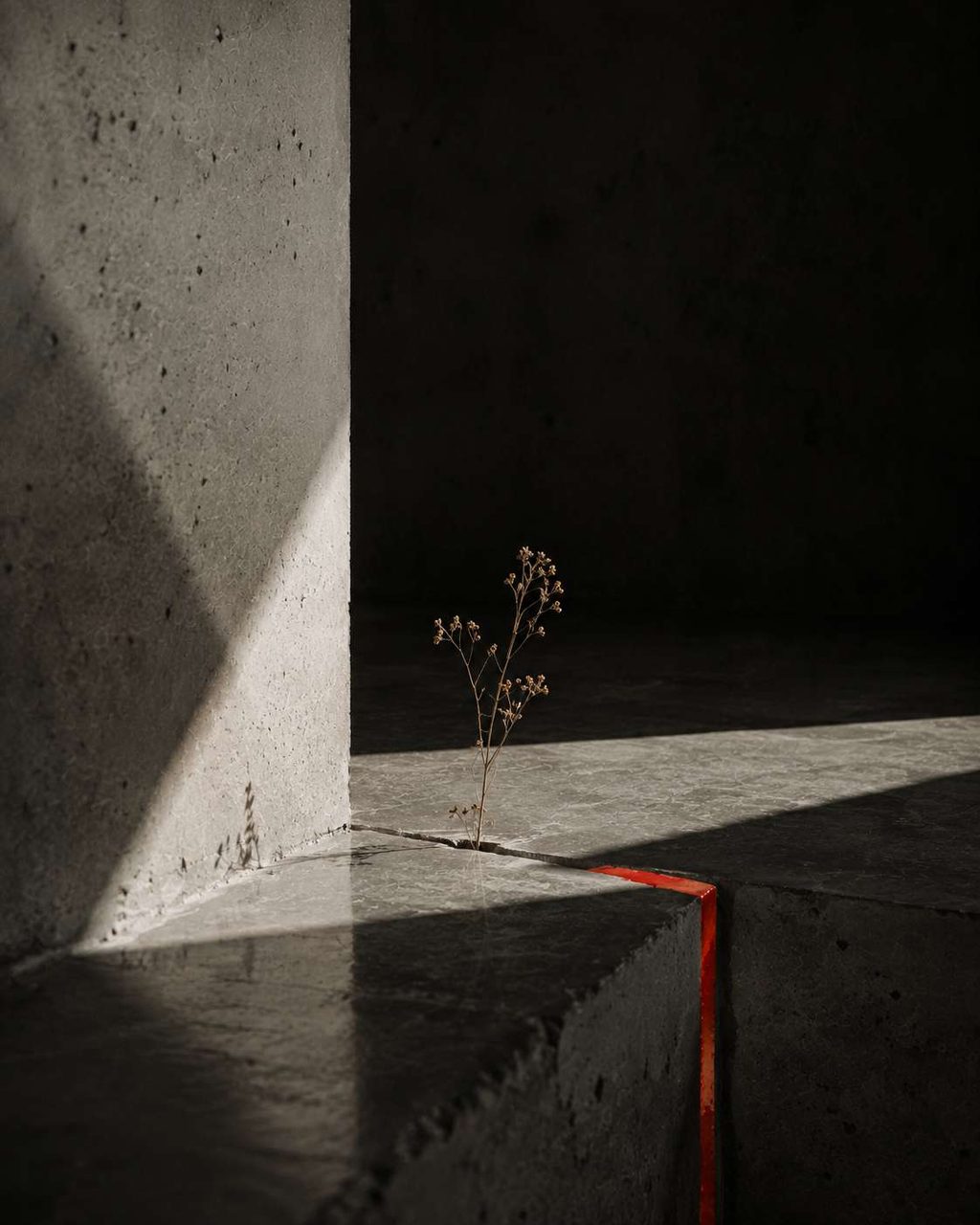 A close study of a concrete edge split by a thin seam of red light.